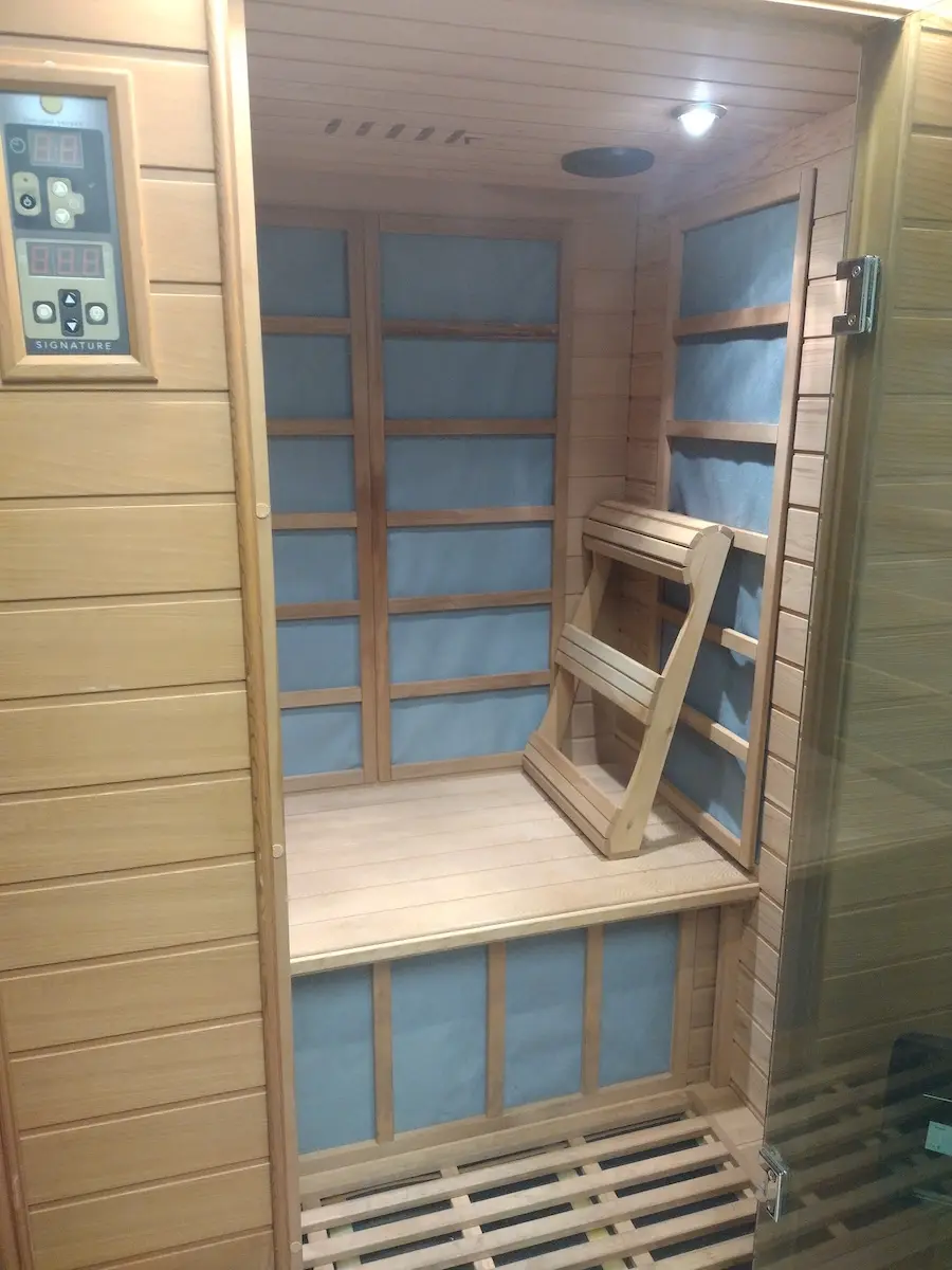 Inside the infrared sauna, warmly lit, with a cedar bench and backrest